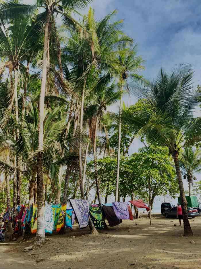 A chill beach vibe with markets for colorful scarves beside the beach under palm trees