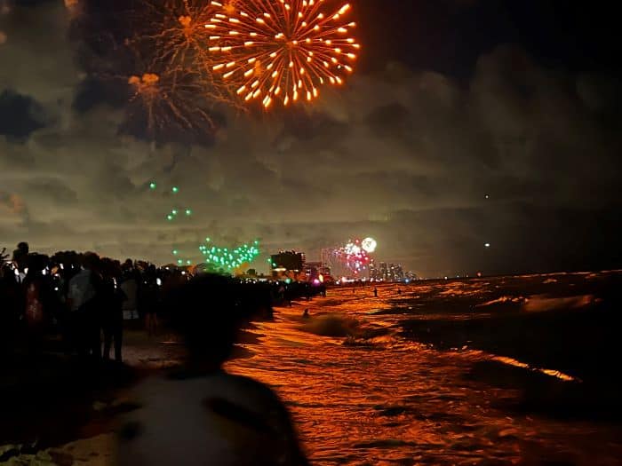 Fireworks in Miami Beach on a dark night, where the colors from the fireworks are reflected in the calm dark sea