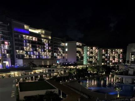 A hotel pool area at night, with blue underwater lights, surrounded by lights from the hotels rooms and lobby area in Melia International Varadero, Cuba