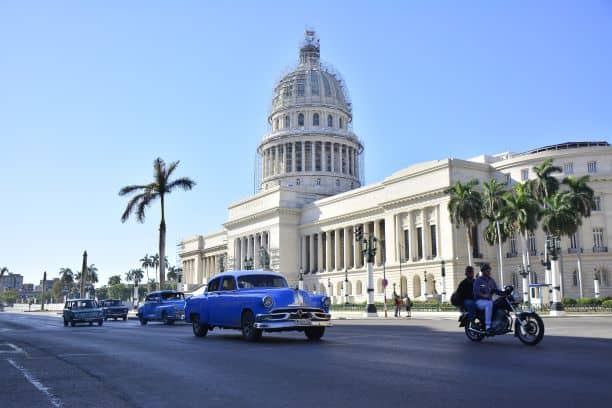 The beautiful capitolio building in Havana, with street life and classic american cars in front