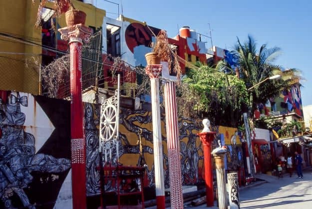 Colorful alley with religious significance, with columns, green plants, and art details in abundance in strong colors