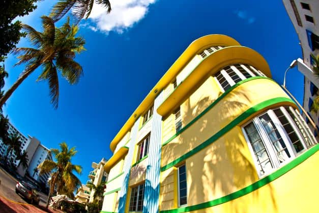 A bright yellow Art Deco house with green details in South Beavh Miami on a bright sunny day with blue skies