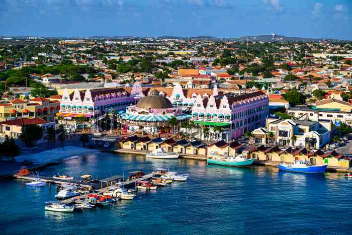 Aerial photo of the port of Oranjestad, the capital of Aruba, with colorful buildings and fun fare, boats along a jetty on the water, on a bright summer day