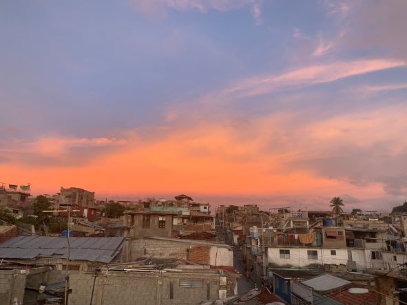 Sunset over Santiago de Cuba, the sky is golden orange, and the rooftops messy and irregular as the city itself
