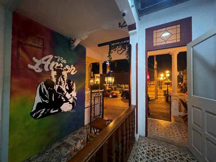 A bar in Puerto Plata at night, with beautiful decor, tiled decorative floors, wall paintings, and a view to the main square outside. 