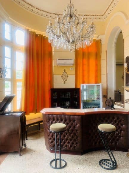 The bar area in Villa Teresa, a leather padded bar front, with bright orange curtains in the back and an old fashioned record player beside the bar. 