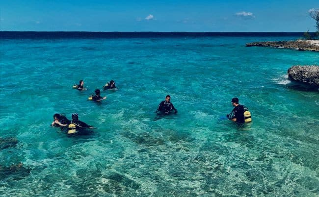 Scuba divers in the water ready to go outside Bay of Pigs in Cuba, the water crystal clear blue, and the sun sparkling in the water