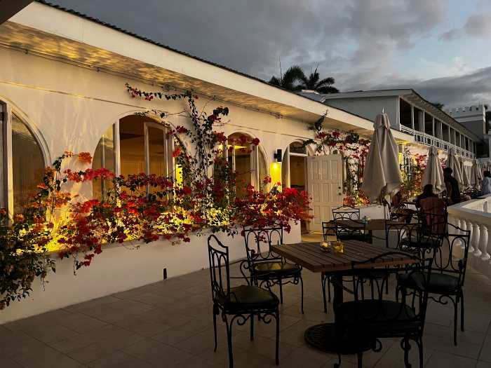 The beautiful patio outside a white building decorated with flowers, with elegant seating areas, in the glowing light from the setting sun