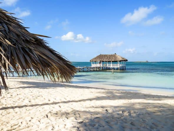 Beautiful beach in Cayo Santa Maria Cuba with white sands, crystal clear water and palm trees with a white charming hut above the water. 