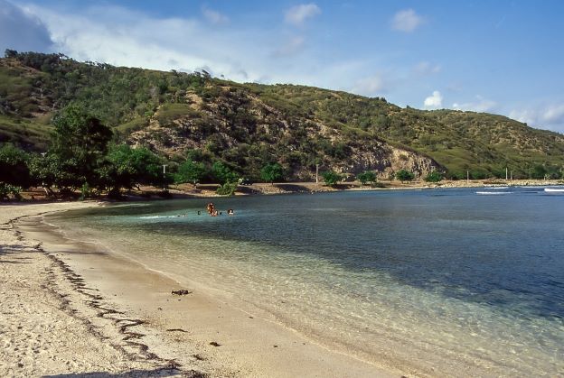 Secluded beach with golden sands below the Sierra Maestra, green hills in the background
