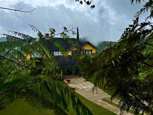 A large secluded yellow villa in the mountains with a big garden surrounded by deep green lush forest