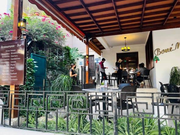 The Bone Ma terrace with outdoor seating, white walls surround the nice area with wooden ceiling and white tables. 