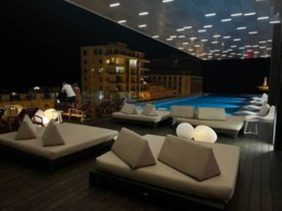 The pool lounge at night at the Grand Packard in Havana with white furniture, blue lit pool, and lots of lights in the ceiling. 