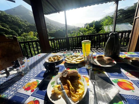 Breakfast table in the morning sun before hiking the Sierra Maestra, the lush green hills and mountains in the background