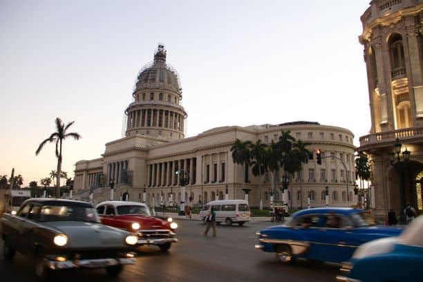 The famous and beautiful Capitolio building in Havana, that used to be the home of the Cuban parliament before the revolution. Here it is right around sunset, with the white cupola on top, and lots of classic American cars along the street in front. 