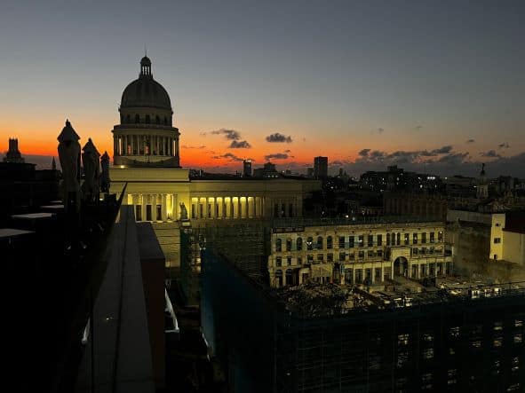 View of the Capitolio from the Bristol rooftop after sunset, with a glowing orange sky behind the Capitolio dome