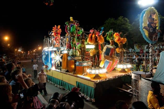 A decorated truck filled with dancers in colorful costumes in the Santiago night