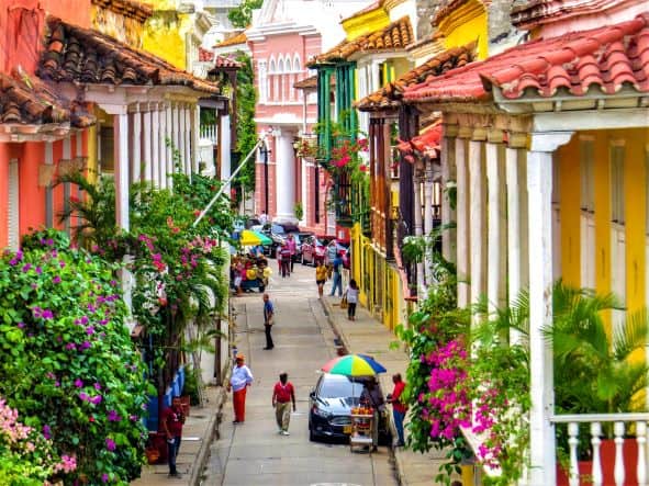 A street in Cartagena Colombia between beautiful colonial buildings covered in flowers and green plants