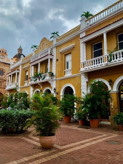 Charming square in Cartagena, surrounded by yellow colonial buildings, decorated with green plants