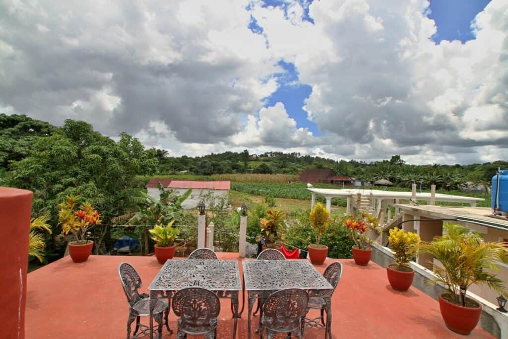 Terracotta Rooftop terrace in Vinales with charming seating, flowers and plants, and stunning views of the green fields of the valley