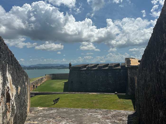 the old fortress Castillo de San Juan on a summer day with green grass, ancient stone structures udner a partly blue sky