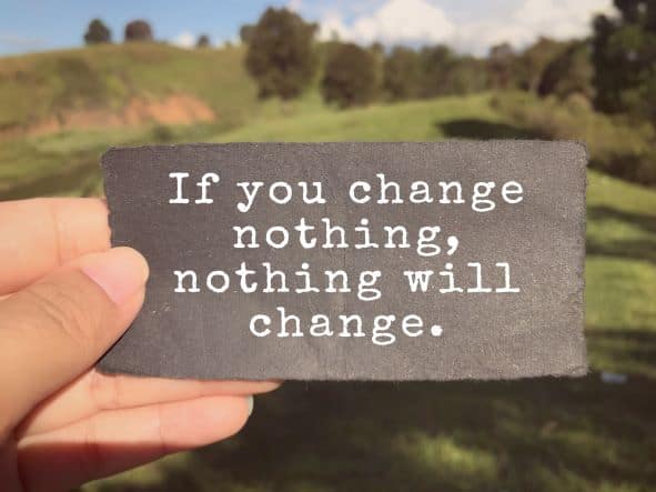 A hand holding a note saying "if you change nothing, nothing will change". 