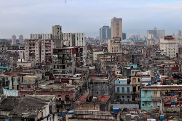 A photo that showes the rugged side of Havana, the run down rooftops and buildings around central Havana towards the Vedado, with thousands of untidy rooftops, a mix og ugly and beautiful on a hazy day. 