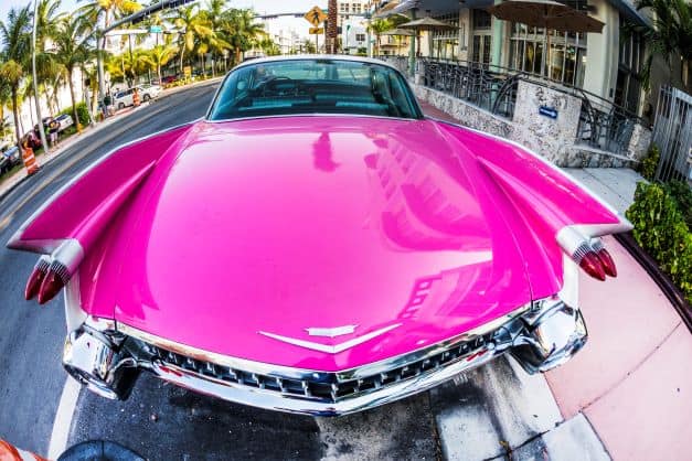 A bright pink shiny classic car from the front on Miami Beach