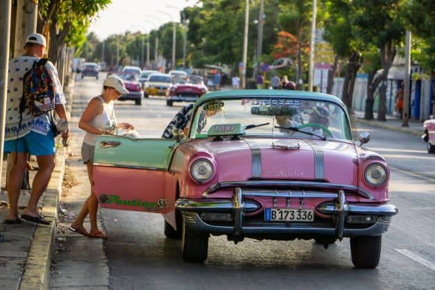 Multi-colored pastel american car in Varadero Cuba picking up a customer