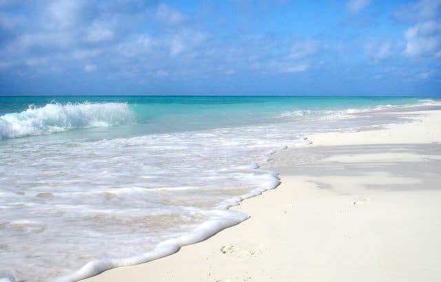 A stunning white sandy beach in the Cuban Keys, white water rolling from the crystal clear water onto the warm sands