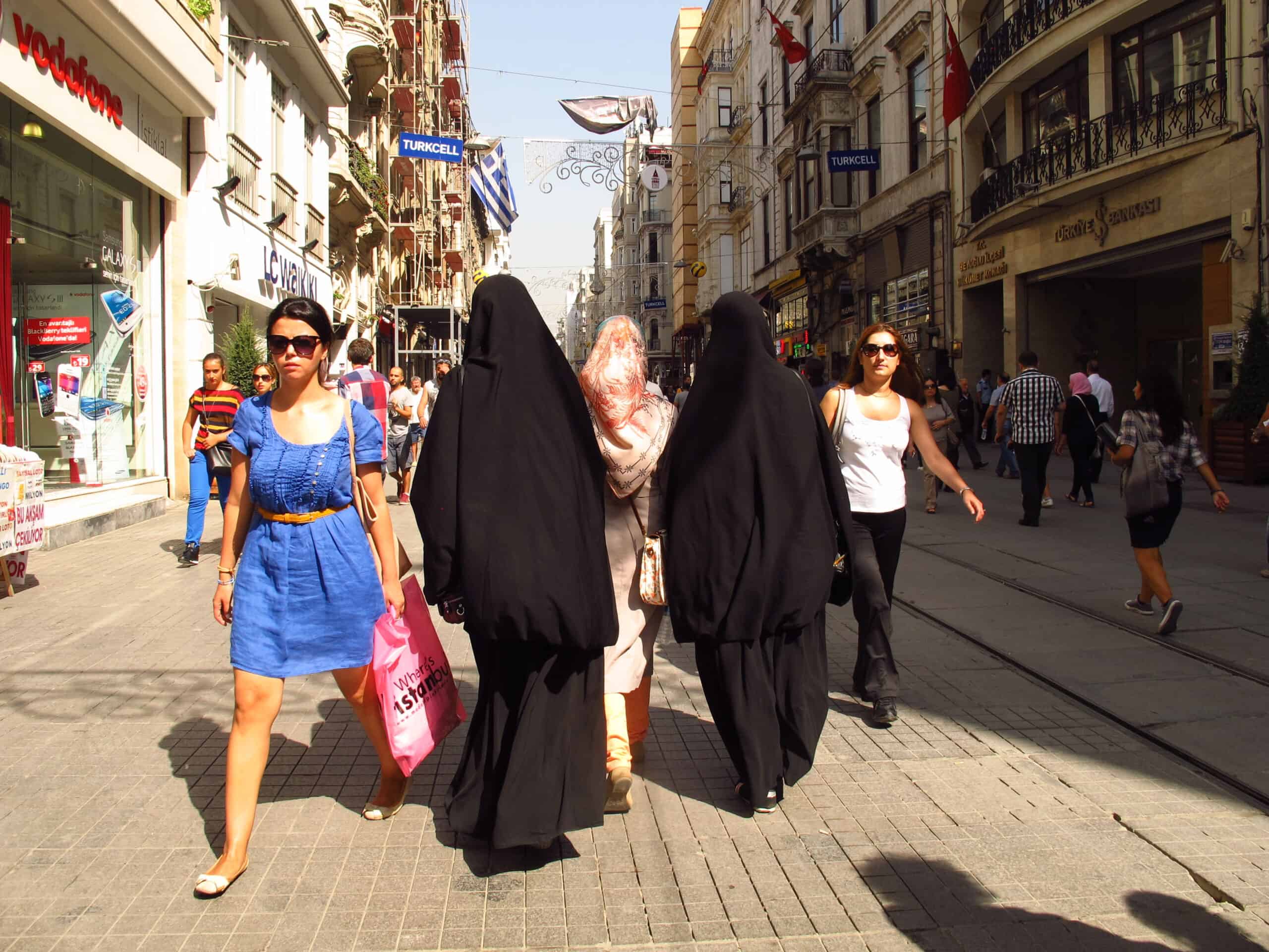 Different perspectives of the world in the same space. Two women walking in light summer dresses, while two others are wearing a long black niqab. 