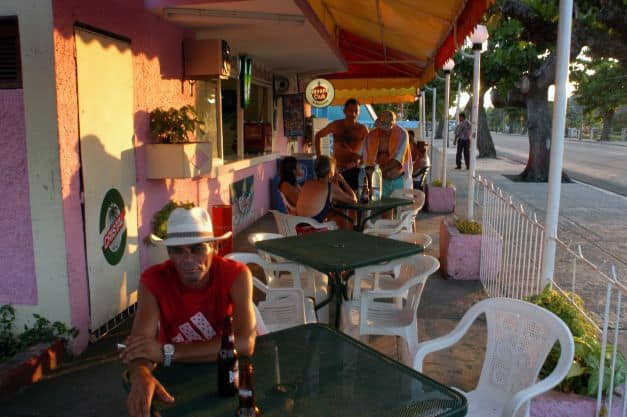 A sidewalk with small cafe tables on a sunny day in Varadero Cuba, people sitting down enjoying the warm sunny day