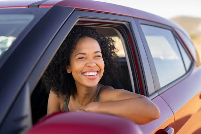 Illustration of a paragraph about rental cars: a woman smiling through the window from inside a red car