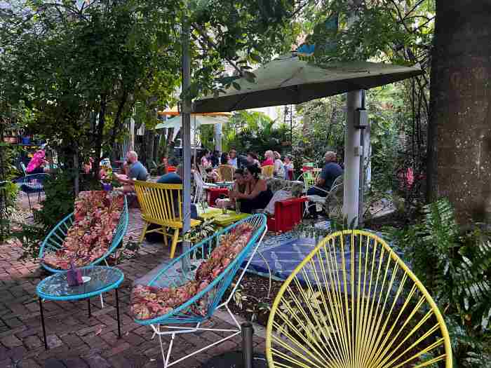The charming backyard at the Freehand Miami, with colorful furniture and lots of green trees and bushes - and people enjoying the afternoon