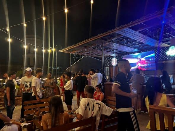 Evening at Bar Galiano 212 in Central Havana, a rooftop bar with lots of local Cubans seated, standing, or dancing in the night lights