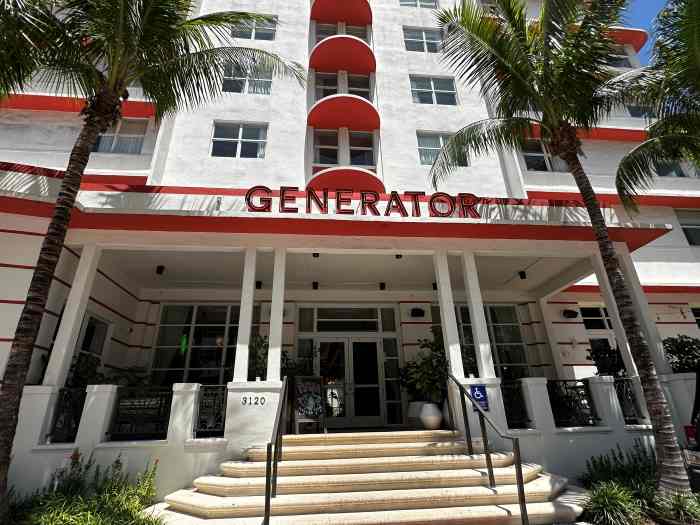 White and red entrance area to the Generator Hotel in Miami Beach on a sunny day with palm trees outside