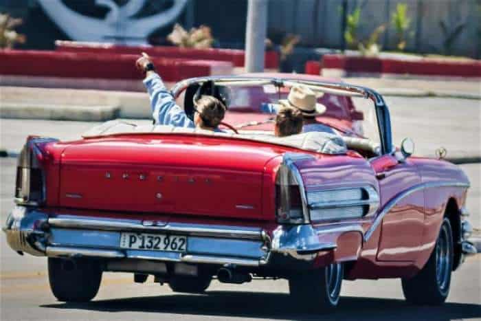 Tourists in a classic American red convertible in Havana, on a bright sunny summer day