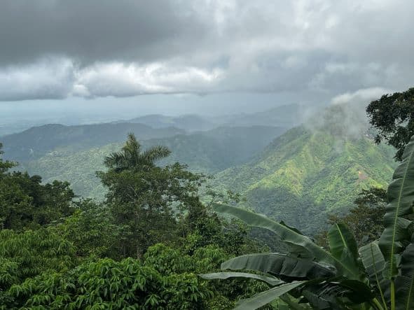 Hazy green infinite views of the Sierra Maestra mountains outside Santiago de Cuba under a cloudy sky with sunlight sifting through