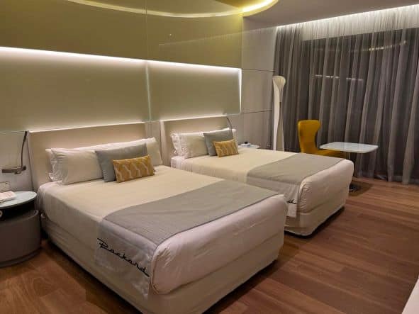 Airy delicate rooms at the Iberostar Grand Packard at night, with two queen beds, and comfortable lighting