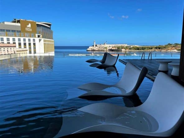 The L-shaped pool at Grand Packard, the sky is reflected in the water, and you can see the fortress and the Morro lighthouse across water of the bay. 