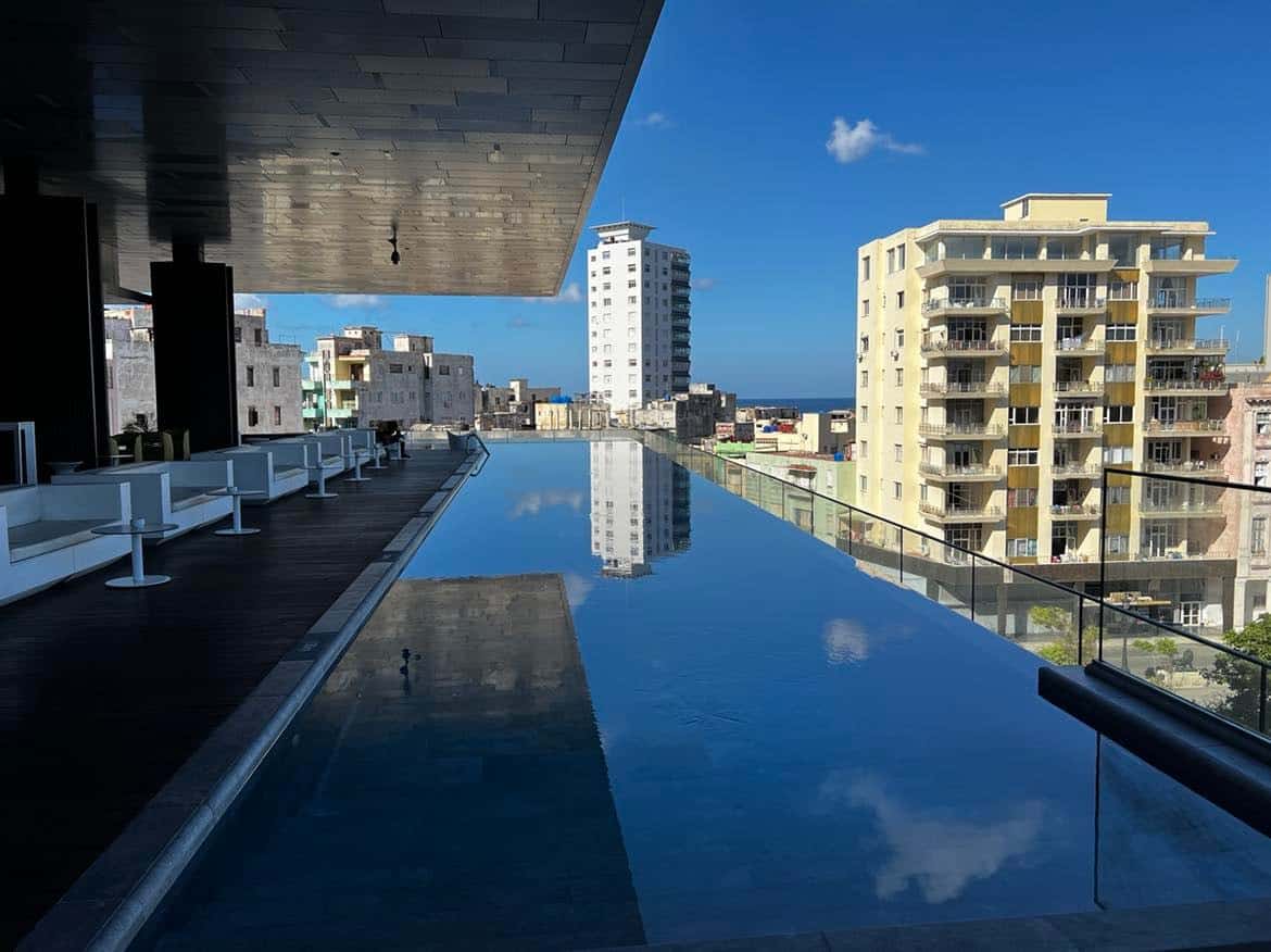 Iberostar Grand Packard infinity pool on a bright summer day, with a view to a typical apartment building that is not very pretty and a bit run down