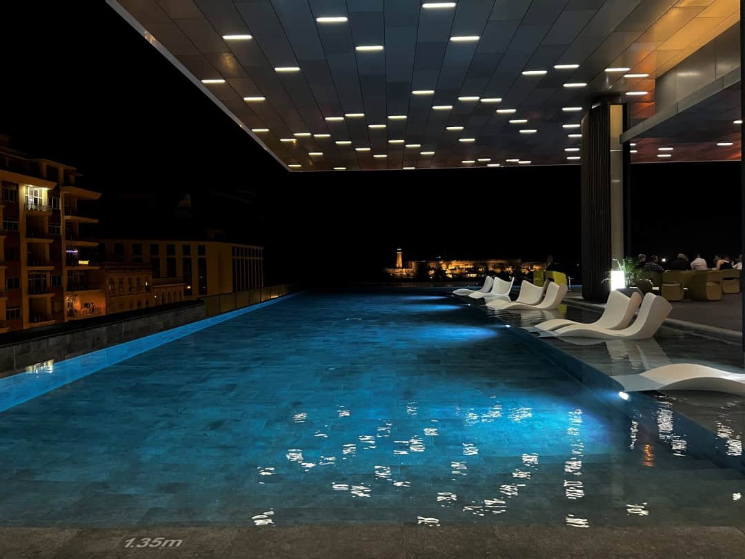 Iberostar Grand Packard Havana at nifht, with a myriad of lights in the outdoor ceiling over the blue lights of the elegant pool