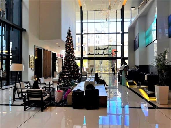 the wide airy Grand Packard foyer decorated for Christmas, with elegant furniture, large glass walls to the outside, and black details 