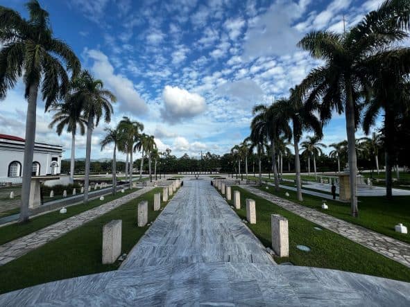 Beautiful scenery in Ifgenia cemetery in Santiago de Cuba, with greyish white marble walkways, lined by palm trees in front of the monument of the father of the homeland. 