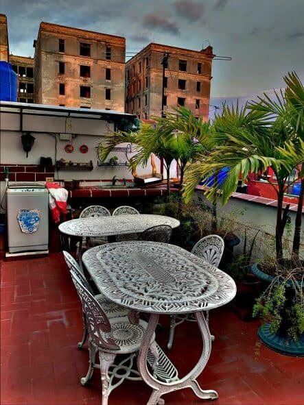 The picturesque red tiled terrace at Jakera spanish school in Havana, with ornate white iron garden furniture