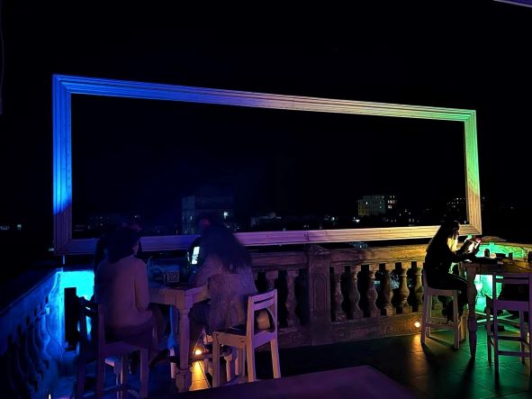 Dark night with lamps lighting the tables at La Guarida rooftop bar, lights from the city in the background. 