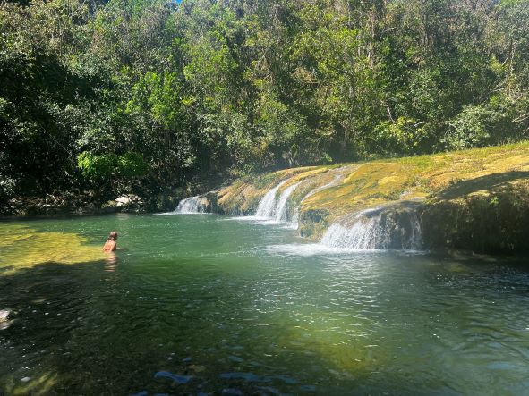 The fresh green water in Las Terrazas in Pinar del Rio province, Cuba. My friend is swimming towards the small beautiful waterfalls of the terraces. 