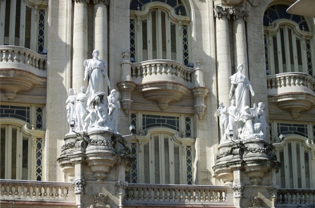 Beautiful elegant marble statues of women with children on an aleborate building in Cuba with huge columns, balconies and art details. 