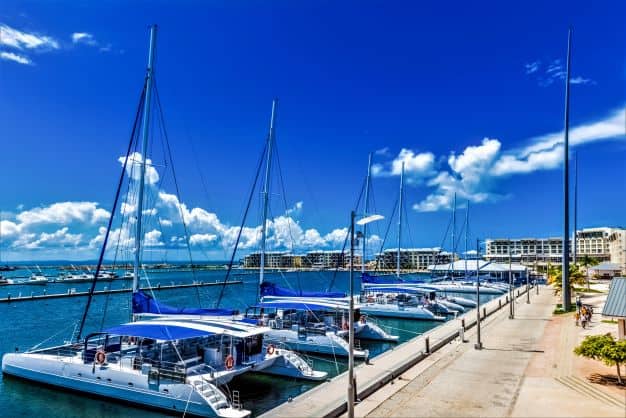 The marina in Varadero where white catamarans are docked like beads on a chain, on the blue water with a backdrop of the even bluer sky. 