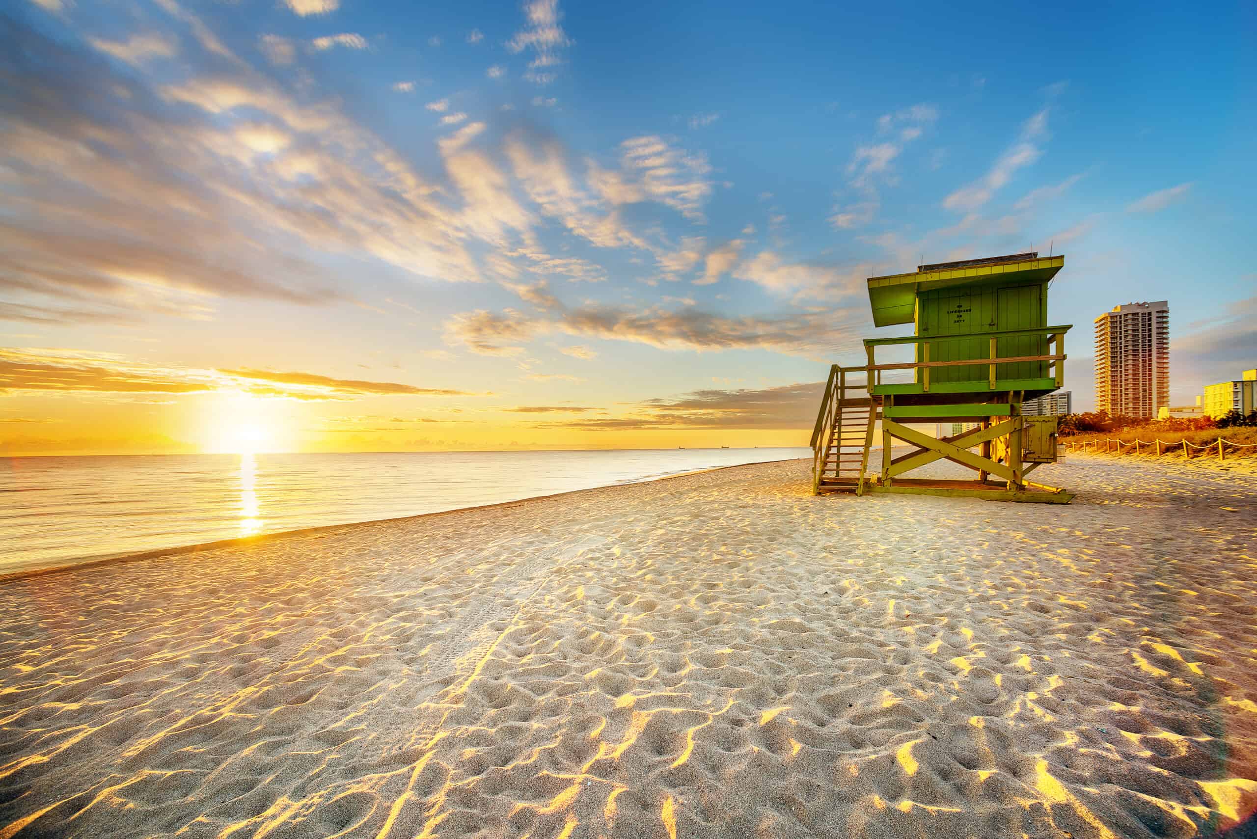 Glowing sunrise over Miami Beach, the white sands and a green lifeguard station
